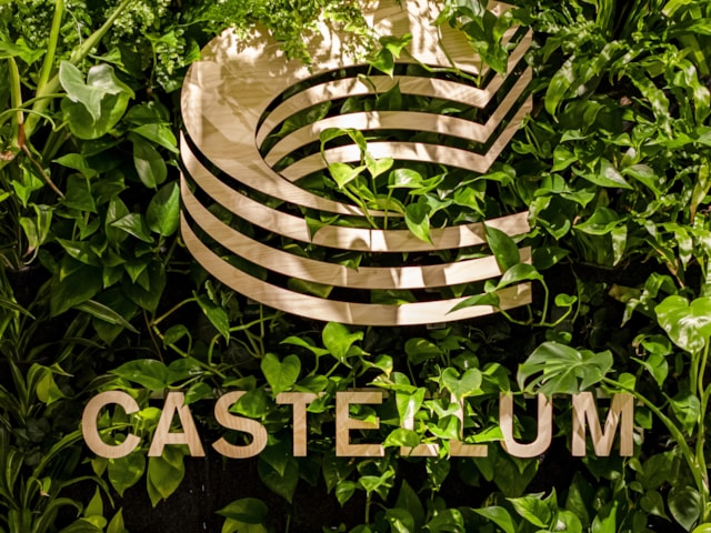 A Castelllum sign against a green wall.