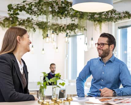 Three people working in a room with green walls.