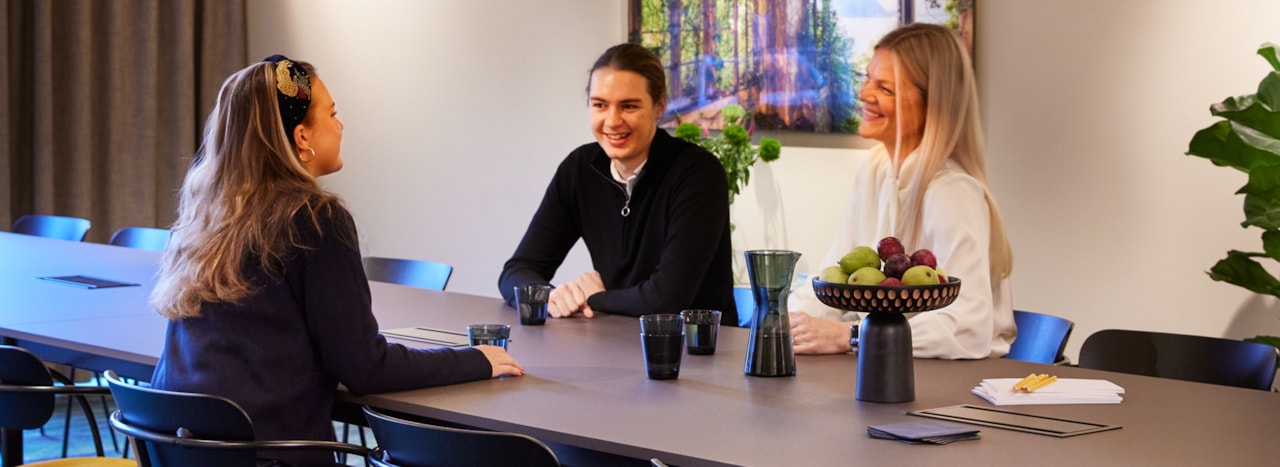 Three people sitting in a meeting room.