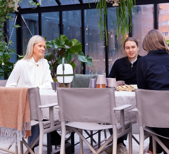 People sitting around a table in a greenhouse.