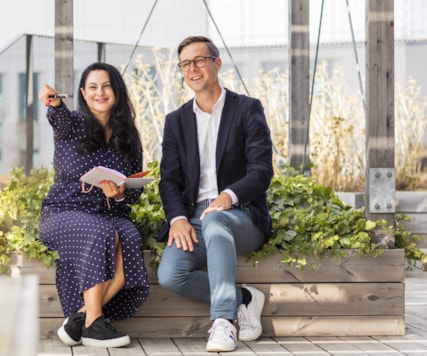 Two people sitting on a bench on a roof top terrace.