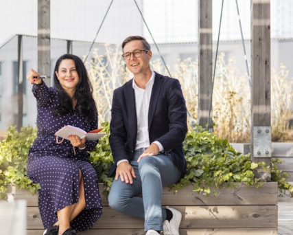 Two people sitting on a bench on a roof top terrace.