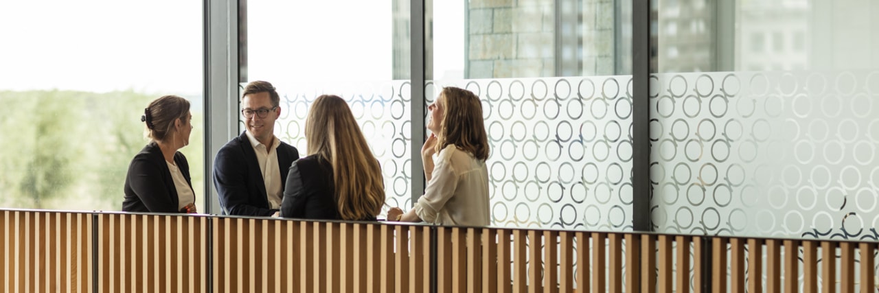 Four people talking on next to a wooden railing.
