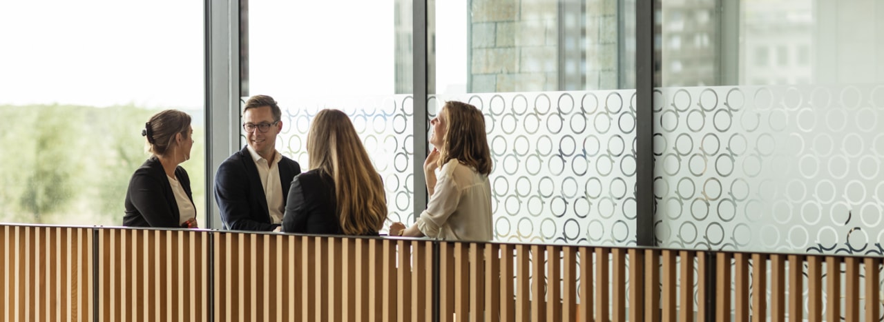 Four people talking on next to a wooden railing.