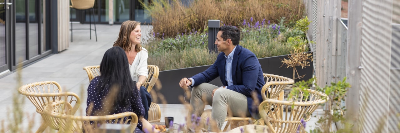 Three people sitting outside talking.