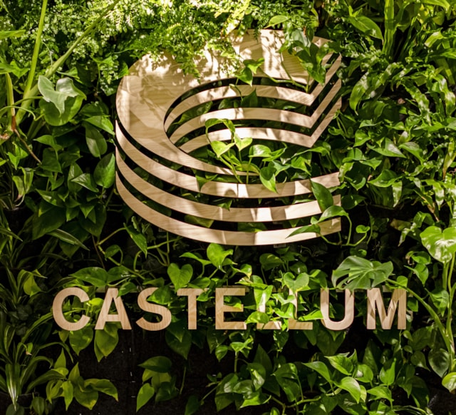 A Castelllum sign against a green wall.