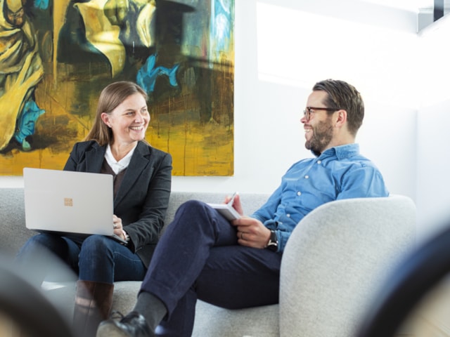 Two people sitting in a sofa smiling.