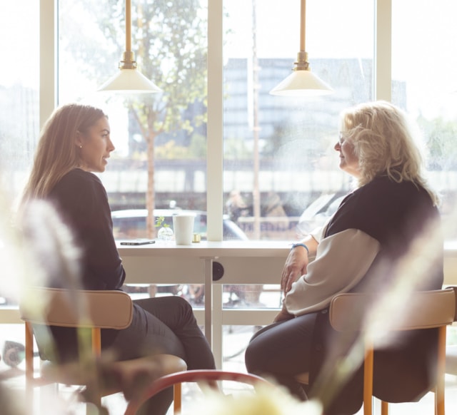 Two people sitting by a window table.