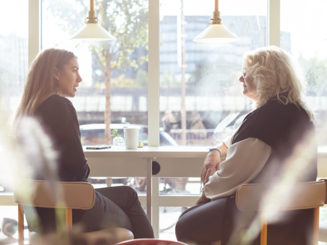 Two people sitting by a window table.