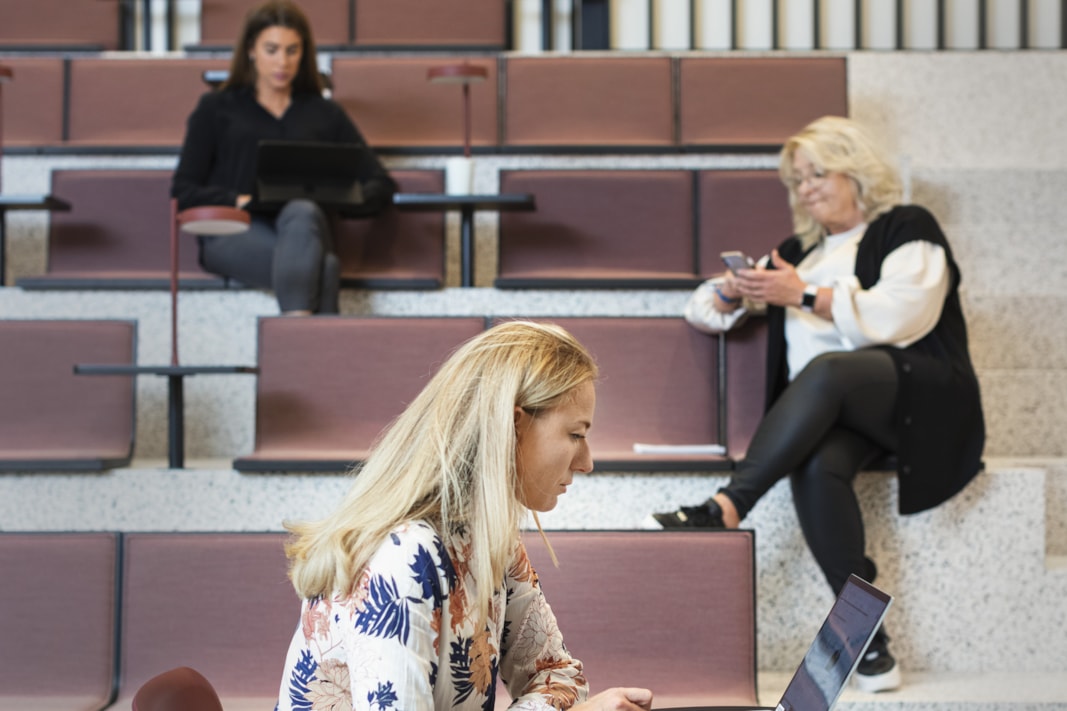 Three people sitting in an auditorium.