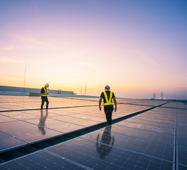 Two people standing on a roof with solar panels.