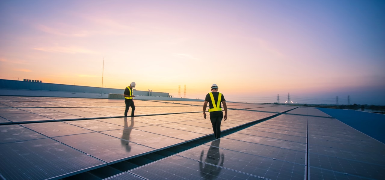 Two people standing on a roof with solar panels.